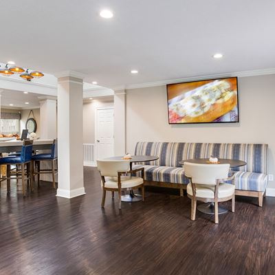 Leasing office interior furnished with an upholstered bench with 2 tables and chairs in front of it at Azure Cove in Garden City, GA
